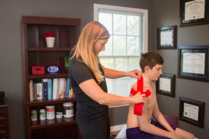 Dr. Meghan Faulkner applying kinesiology taping to young man